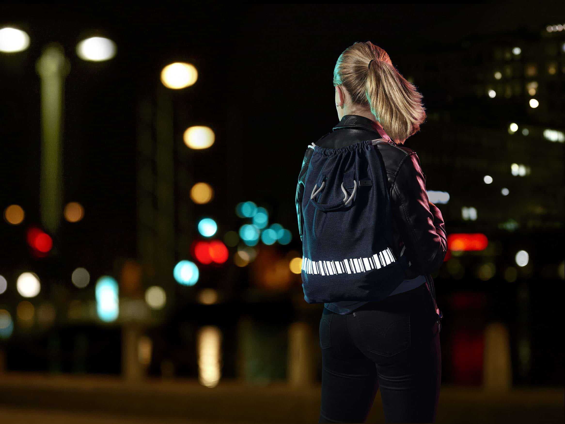 Gymbag i vattenavvisande svart tyg med en reflexslinga i mönstret norrsken nertill. Handtag.
