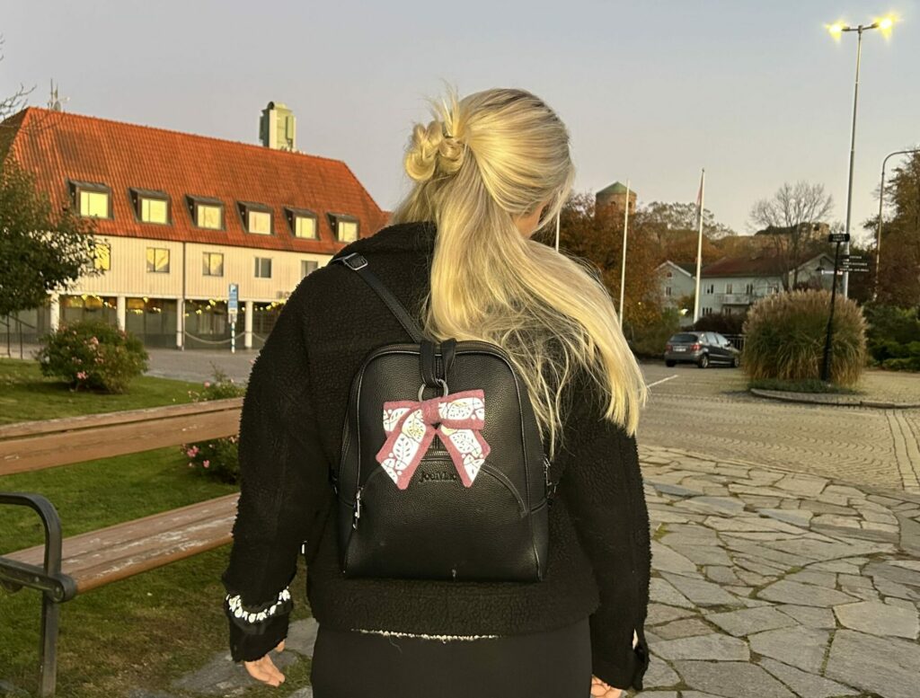 tjej med snygg reflexrosett, bag charm, på ryggsäck och rynkad armreflex, från Smart in the dark