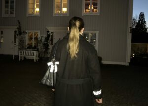 tjej med snygg reflexrosett, bag charm, på handväska, och snygg rynkad armreflex, från Smart in the dark